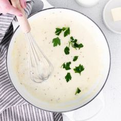 a bowl filled with cream and parsley on top of a table next to other dishes