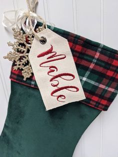 a christmas stocking hanging on the door with a name tag attached to it and snowflakes