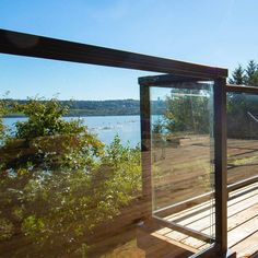 a wooden deck with glass railing overlooking the water