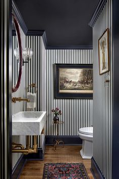 a bathroom with black and white striped walls, wood flooring and an antique sink