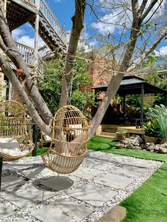 a hammock hanging from a tree next to a patio with grass and rocks