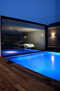 an indoor swimming pool is lit up at night with lights shining on the wall and wood flooring