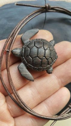 a small turtle sitting on top of a leather cord