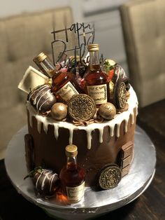 a birthday cake decorated with liquor bottles and candies is on a silver platter