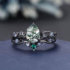 a close up view of a ring with an emerald stone and crystal stones on it