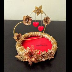 a gold crown with flowers and hearts on it sitting on a table next to a wall