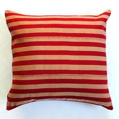 a red and white striped pillow sitting on top of a white table next to a wall