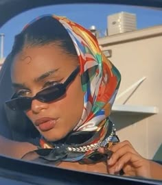 a woman wearing sunglasses and a scarf in a car