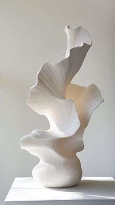 a white sculpture sitting on top of a table next to a light colored wall and floor