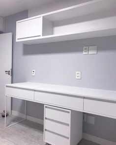 a white desk with drawers and shelves in an empty room next to a door that leads into another room