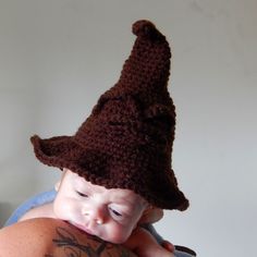 a baby wearing a brown crocheted wizard hat