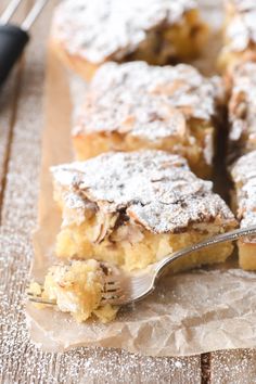 a piece of cake with powdered sugar on top and a fork in the foreground