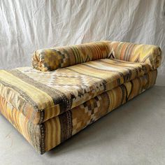 a multicolored couch sitting in front of a white backdrop