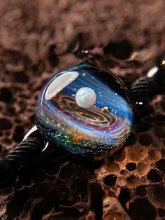 Introducing our exquisite "Galaxy Glass Gemstone Pendant/Bracelet" - a stunning piece of handcrafted jewelry that beautifully showcases your love for the universe. Meticulously crafted by skilled artisans, the pendant and bracelet feature a blend of gold, silver, and gemstones, all embedded in a special glass that's been carefully carved to create a floating effect. The result is a breathtaking display of shimmering colors that come to life in the light. This product features pure 24K Gold bead and exquisite Opal gemstones, which offer a rainbow of colors and the beauty of multiple gemstones fused into one. The high-hardness borosilicate glass shell protects the gold, silver, and gemstones, ensuring that they will never fade or discolor naturally. The pendant and bracelet cords are made fr Astronomy Jewelry, Solar System Bracelet, Cosmic Jewelry, Galaxy Pendant, Planet Necklace, Space Jewelry, Celestial Jewelry, Gift Ideas For Men, Unique Handmade Jewelry