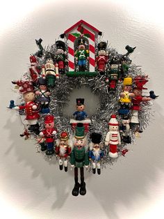 a christmas wreath with toy soldiers and other holiday decorations hanging on the wall behind it