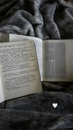 an open book sitting on top of a bed next to a heart shaped paper cutout