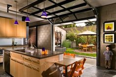 a man standing in front of a kitchen with an open floor plan and outdoor dining area