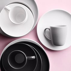 three cups and saucers on a pink surface with one cup in between the two plates