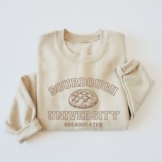 Stay warm and stylish in our SOURDOUGH UNIVERSITY ADULT CREWNECK SWEATER. Made for adults, this sweater features a classic sand color and is made from high-quality materials for maximum comfort. Perfect for chilly days, this sweater is a must-have for any fashion-forward individual. Please review size chart for the perfect fit. Everyday Cream Crew Neck Sweatshirt, Beige Crew Sweatshirt With Ribbed Cuffs, Cream Crew Neck Sweatshirt With Letter Print, Cream Crew Neck Sweatshirt For Fall, Relaxed Fit Cream Sweater With Letter Print, Beige Relaxed Fit Sweater With Letter Print, Beige Crew Sweatshirt For Winter, Beige Crew Neck Sweatshirt For Fall, Beige Crew Neck Sweatshirt For Winter