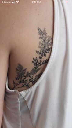 the back of a woman's shoulder with flowers and leaves tattooed on her arm