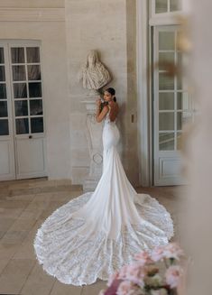 a woman in a white wedding dress taking a photo with her cell phone while standing next to a statue