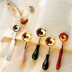 five spoons are lined up in front of an open book on a table top