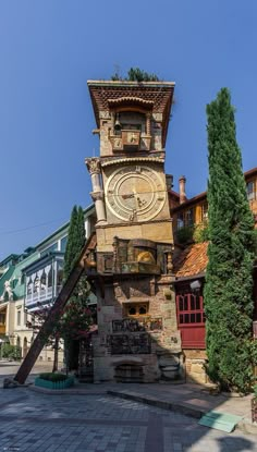 a large clock tower sitting on the side of a road next to tall buildings and trees