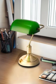 a green lamp sitting on top of a desk next to a calculator