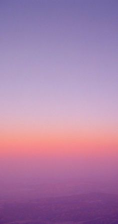 an airplane wing flying in the sky at sunset or dawn with pink and purple hues