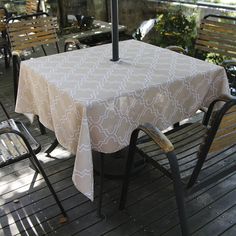 an umbrella sits on top of a table with chairs around it and tables in the background