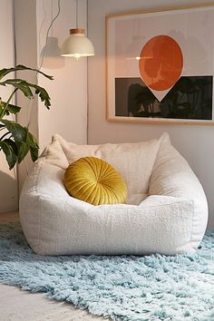 a white bean bag chair sitting on top of a rug next to a potted plant