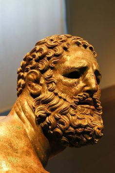 a statue of a man with long hair and beard wearing a gold colored headdress