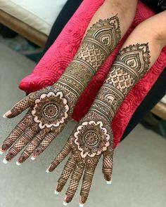 two hands with henna tattoos on them, one is showing off the intricate design