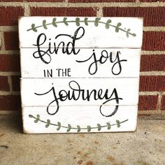 a wooden sign that says find joy in the journey on top of a brick wall