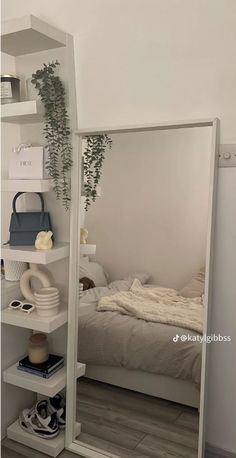 a bedroom with a bed, mirror and shelves on the wall next to each other