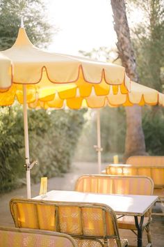 an outdoor dining area with yellow chairs and umbrellas