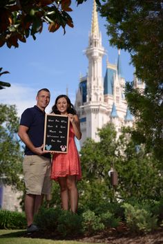 a man and woman holding up a sign in front of a castle