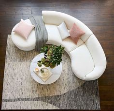 an overhead view of a living room with white couches and pillows on the coffee table