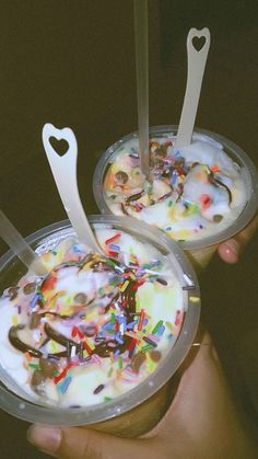 two cups filled with ice cream covered in sprinkles and hearts on top