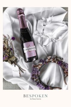 a bottle of wine sitting on top of a white cloth next to a flower wreath