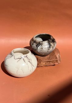 two white vases sitting on top of a rock