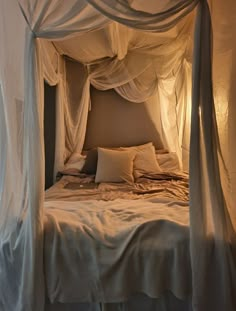 a canopy bed with white drapes and pillows