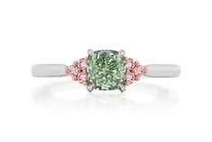 a green diamond ring with pink diamonds on the sides and an oval cut stone in the center