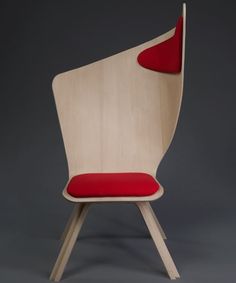 a wooden chair with a red cushion on the seat and backrest, against a gray background