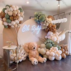 there is a teddy bear sitting next to balloons and other decorations on the wall behind it