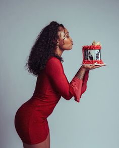 a woman in a red dress holding a cake