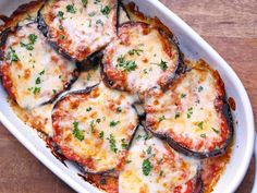 a casserole dish with eggplant slices and cheese on top, sitting on a wooden table