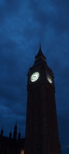 the big ben clock tower towering over the city of london at night with clouds in the sky