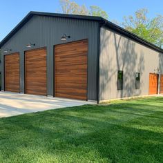 a large garage with two doors on the side of it and green grass in front