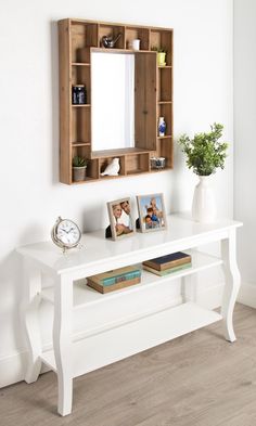 a white table with a mirror and some pictures on it next to a vase filled with flowers